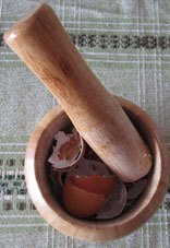 Mortero de madera con cáscaras de huevo a triturar.